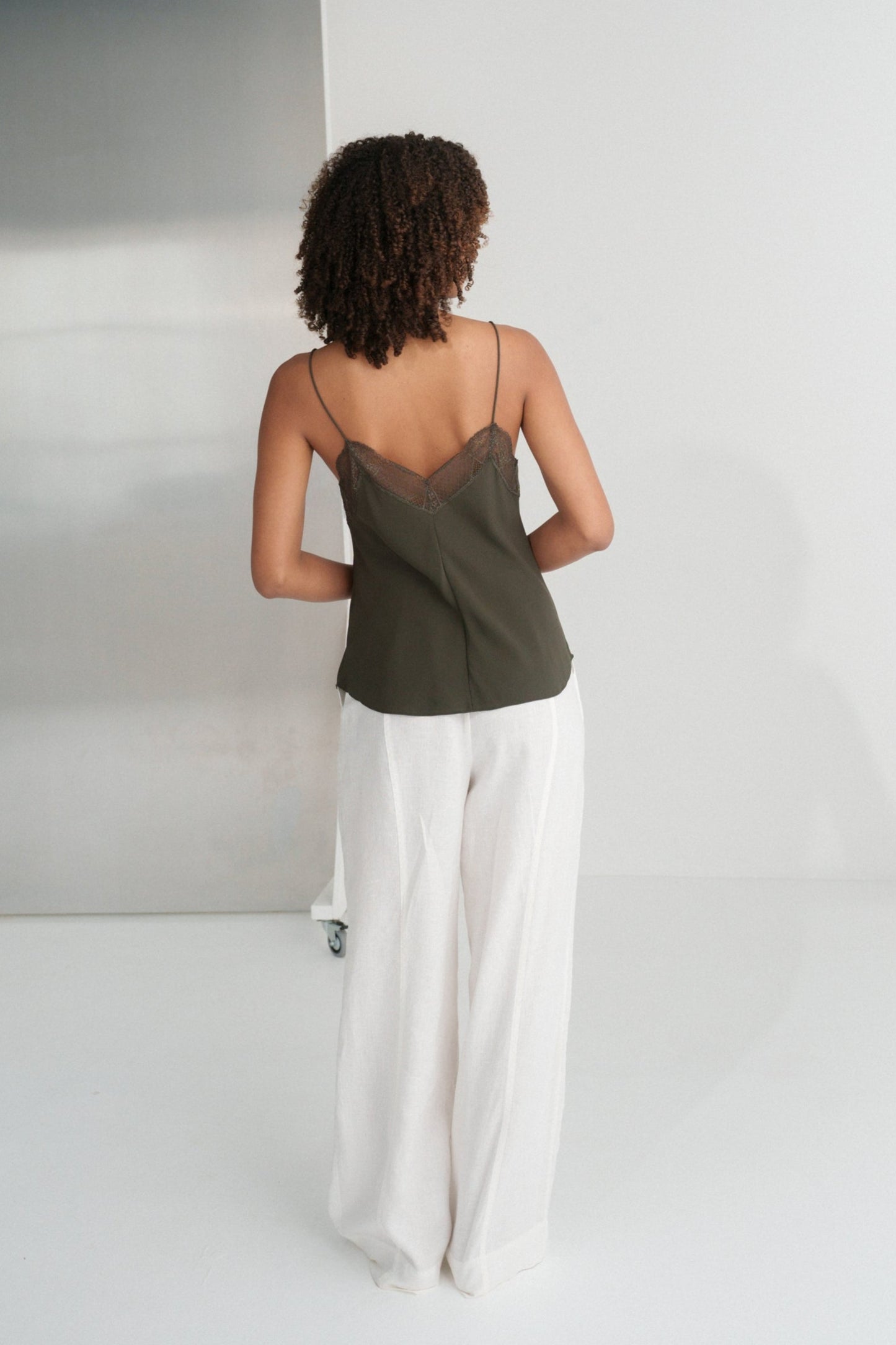 LILLY PILLY woman wearing Frankie silk cami in khaki and Oli linen pants in ivory, back view