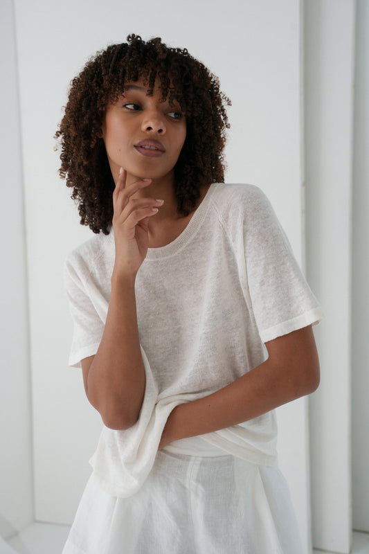 Woman wearing a Grace knit top in Ivory against a plain background