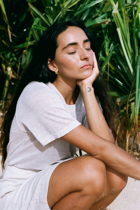 Woman wearing Grace linen knit top sitting outdoors with greenery in the background