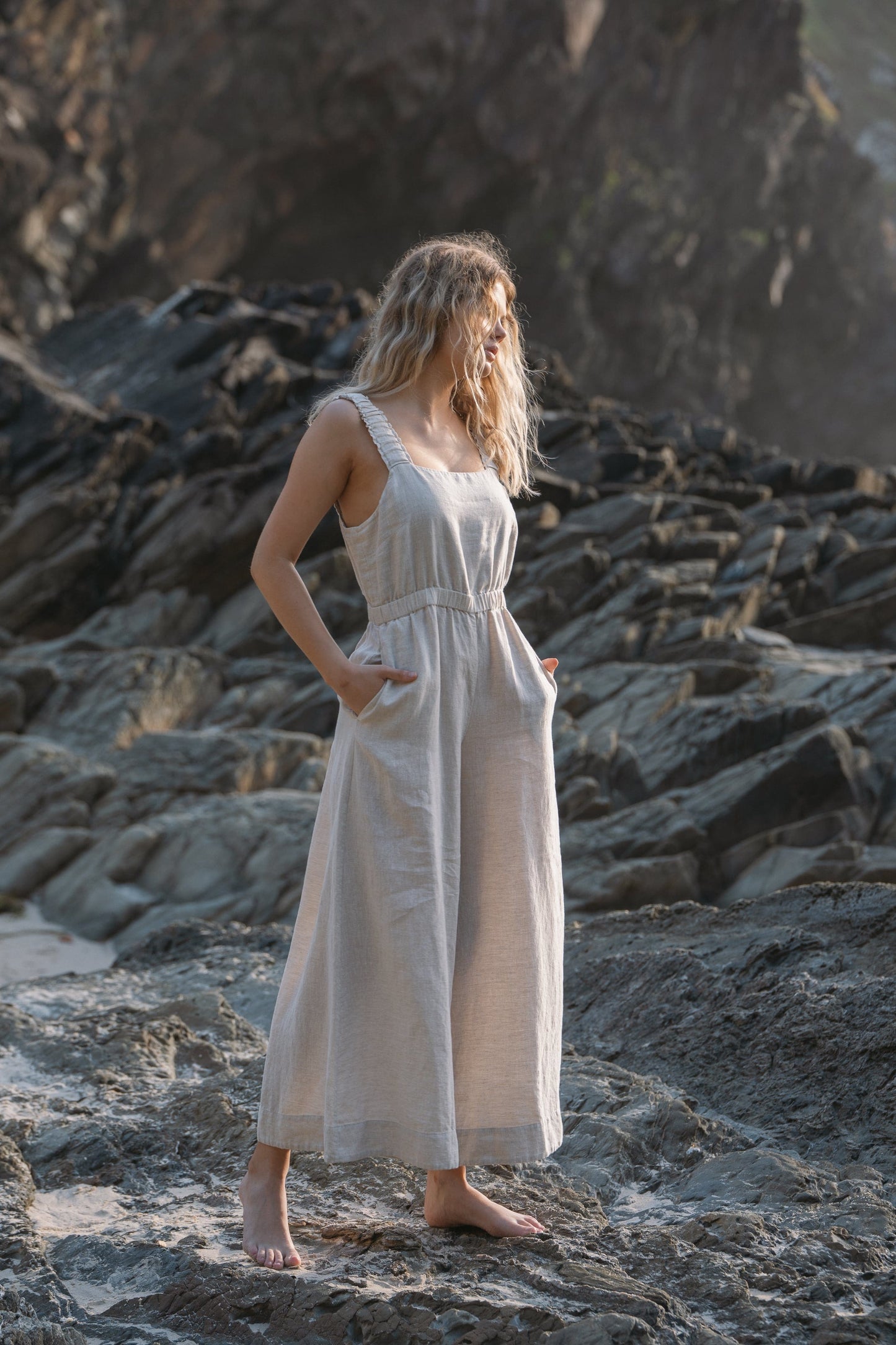 Lilly Pilly Collection European linen Keely jumpsuit in Oatmeal standing on rocks