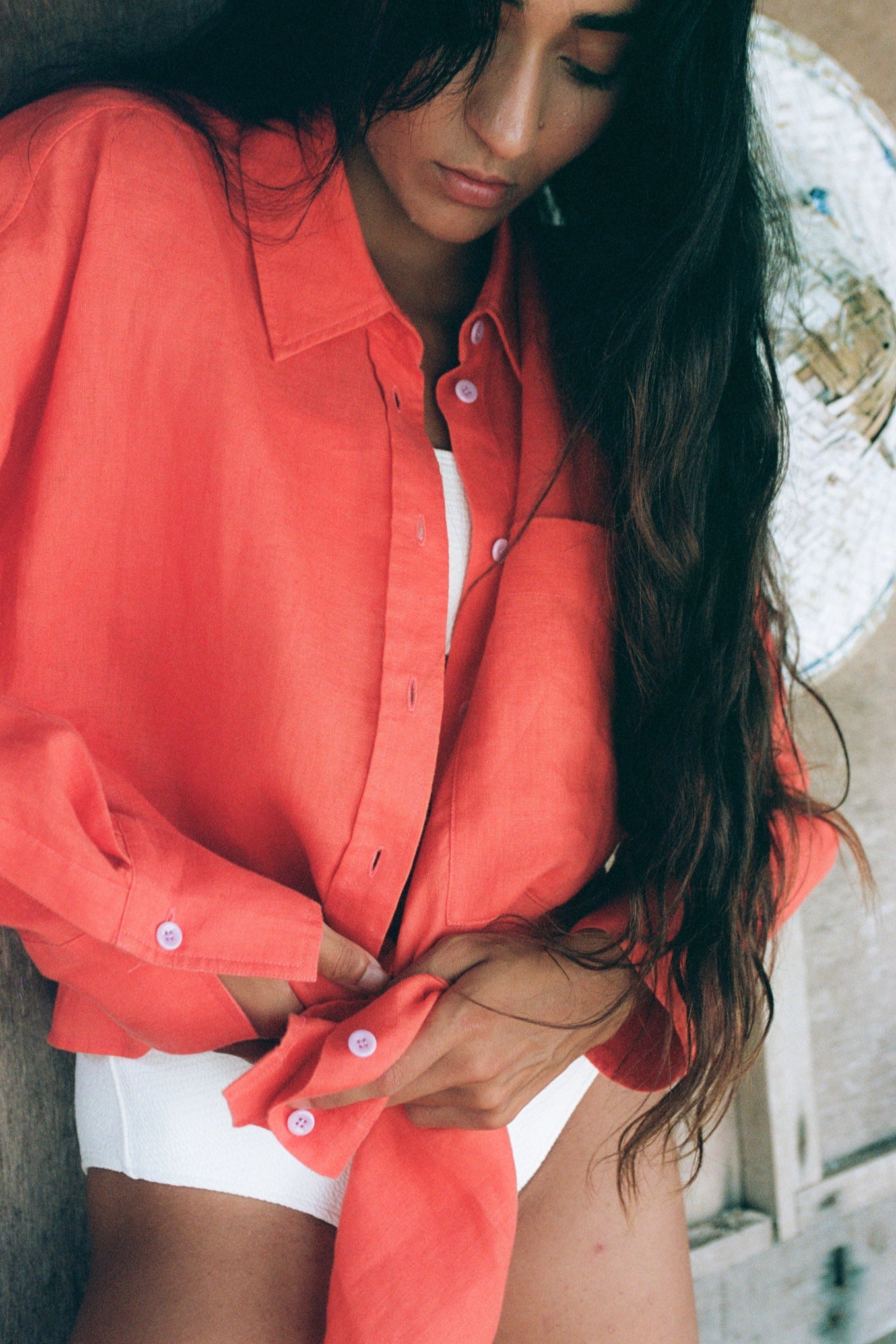 Close up of LILLY PILLY woman wearing a spritz Kirra linen shirt leaning against a neutral background.