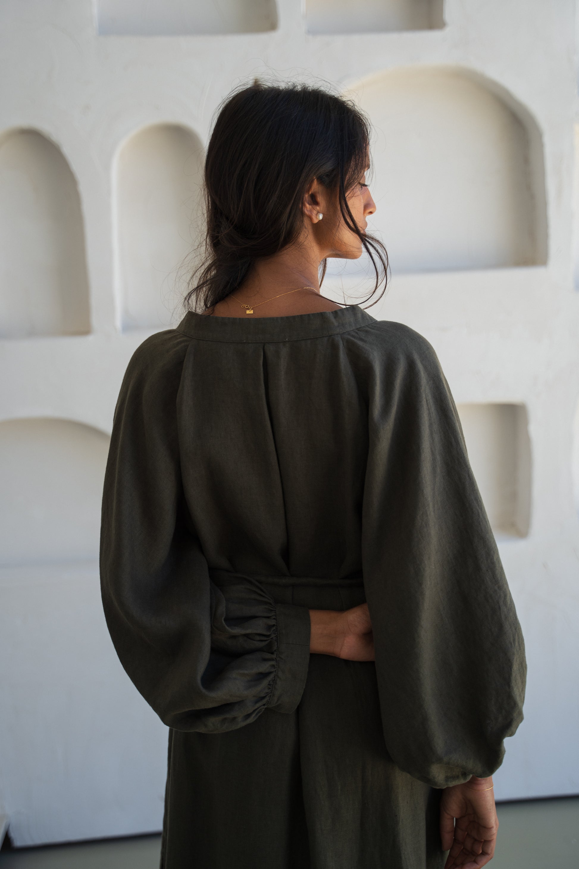 Woman wearing a khaki Mae linen dress in studio, back view close up