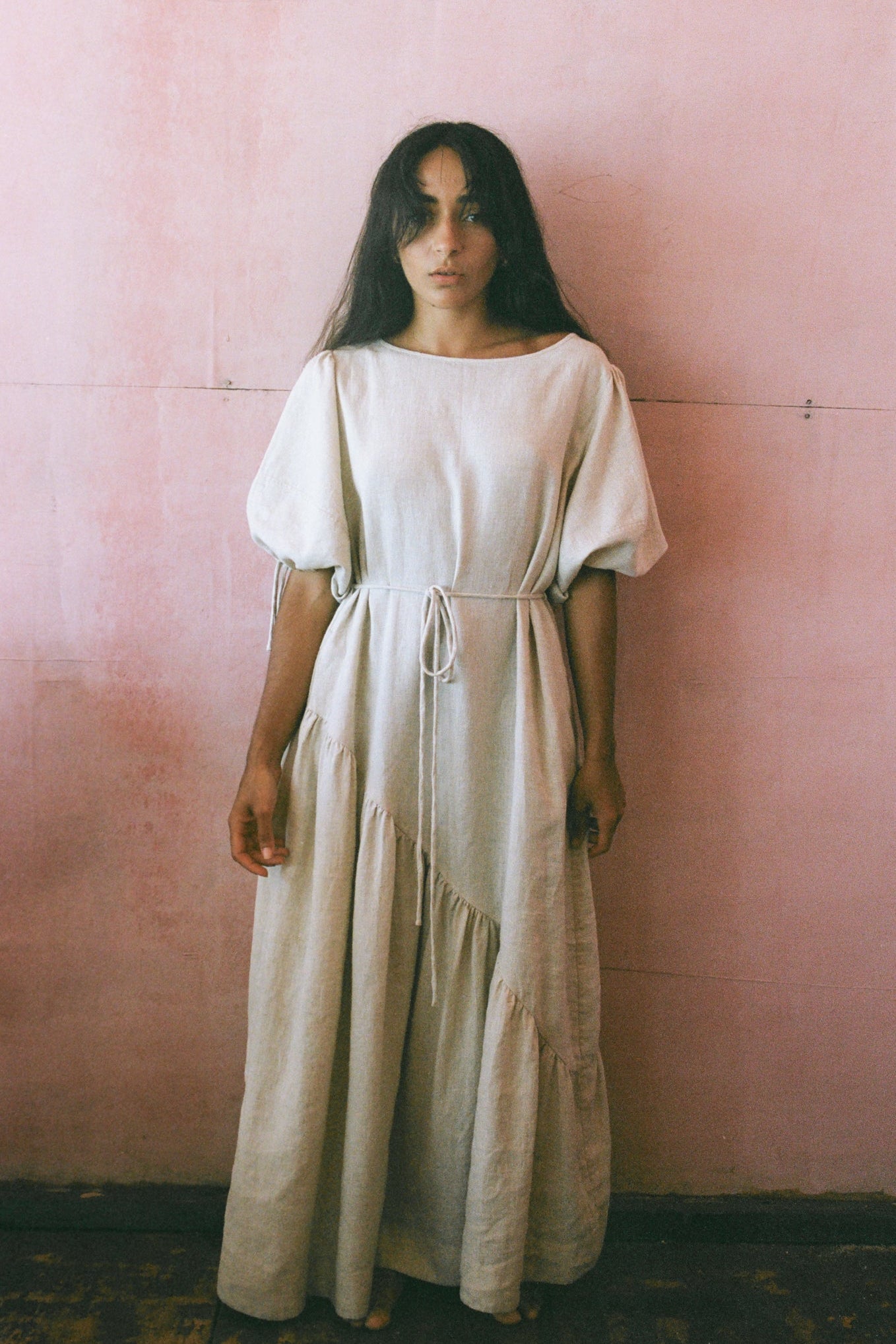 LILLY PILLY woman in an oatmeal Charlotte dress front view standing against a pink wall