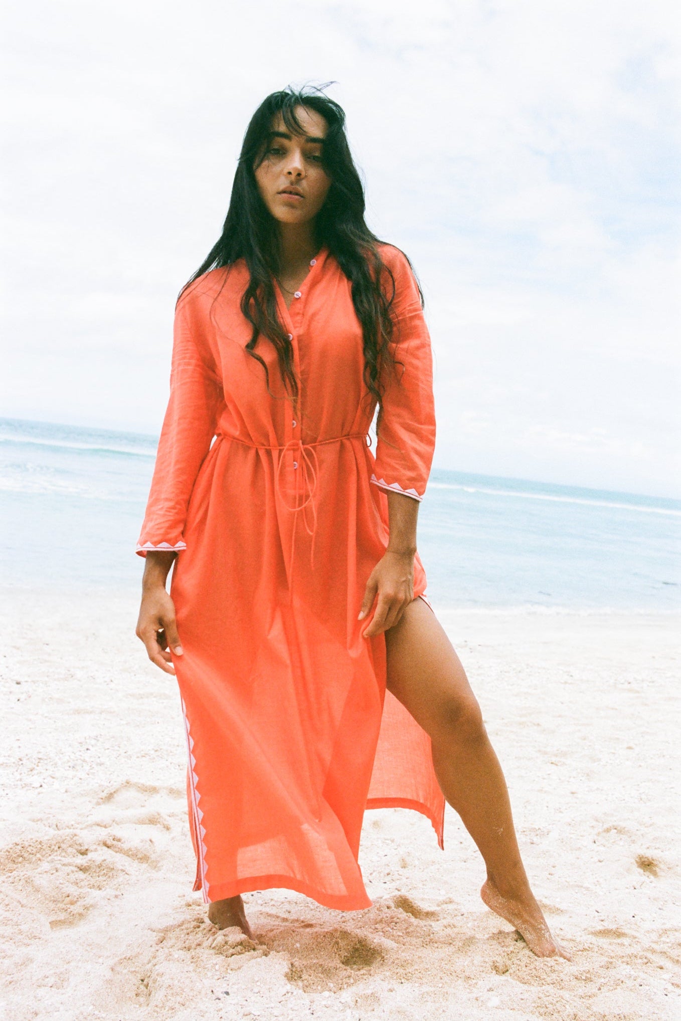 LILLY PILLY woman in a spritz Callie cotton dress standing on a beach with ocean in the background