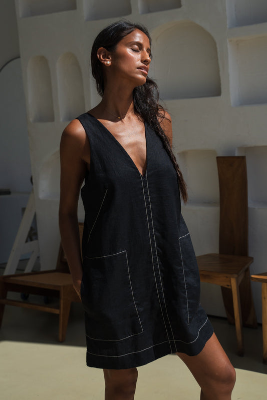 LILLY PILLY woman in an black Isla linen dress with white stitching in an indoor setting