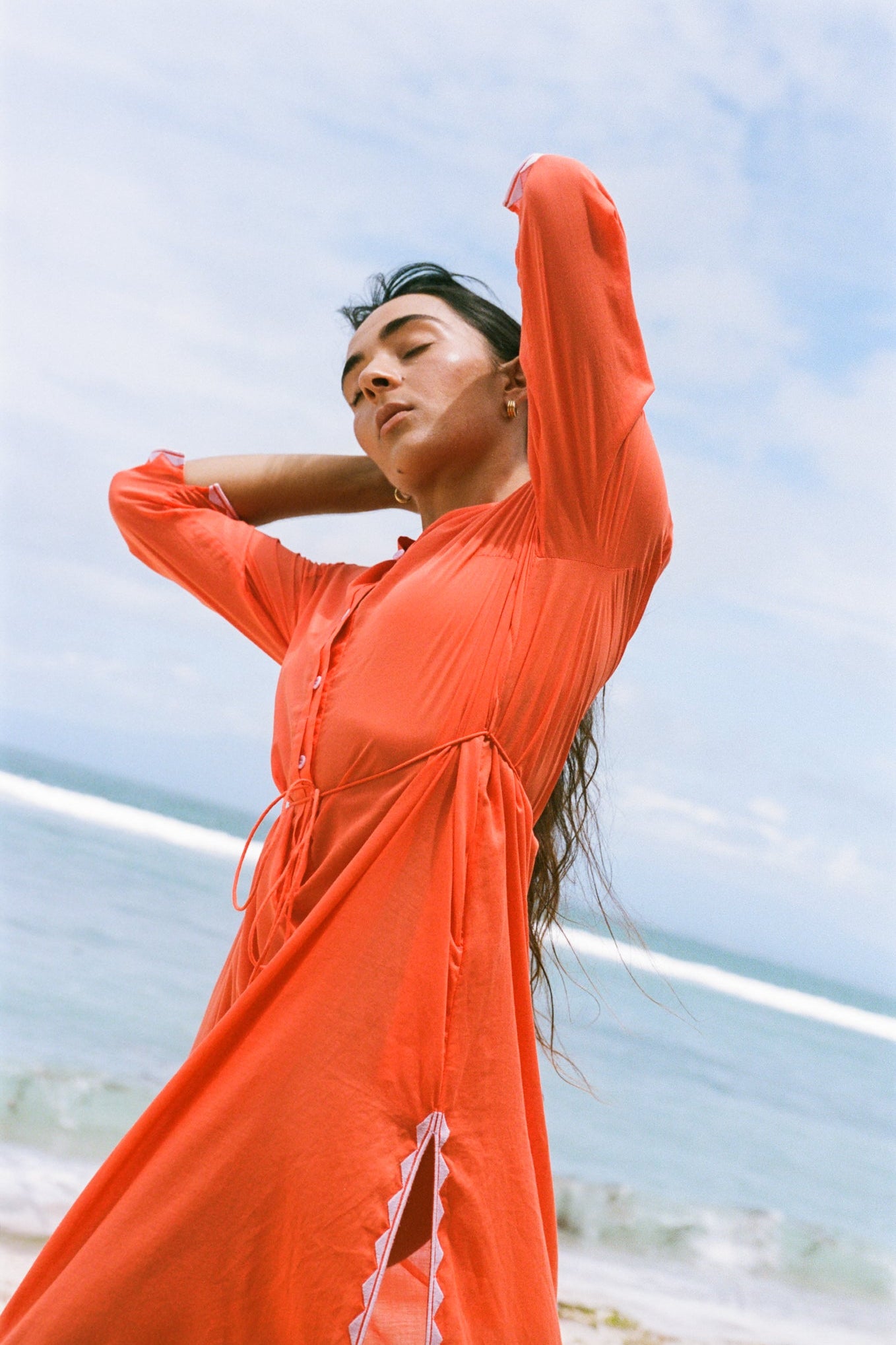 LILLY PILLY woman in a spritz Callie cotton dress standing against a blue sky.