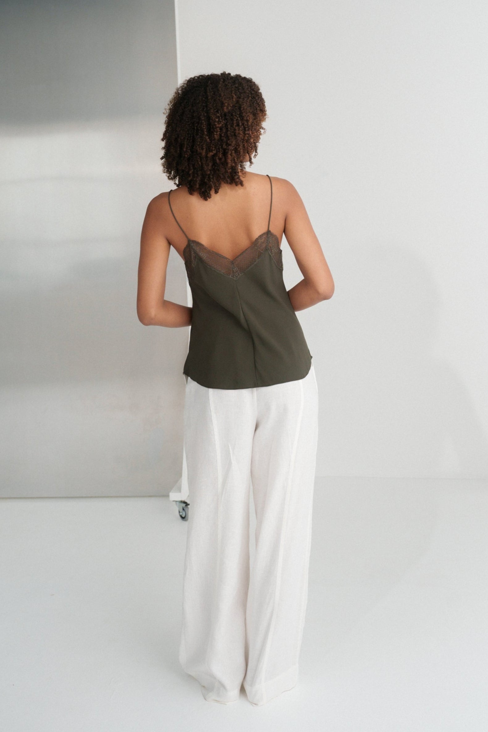 LILLY PILLY woman wearing Frankie silk cami in khaki and Oli linen pants in ivory, back view