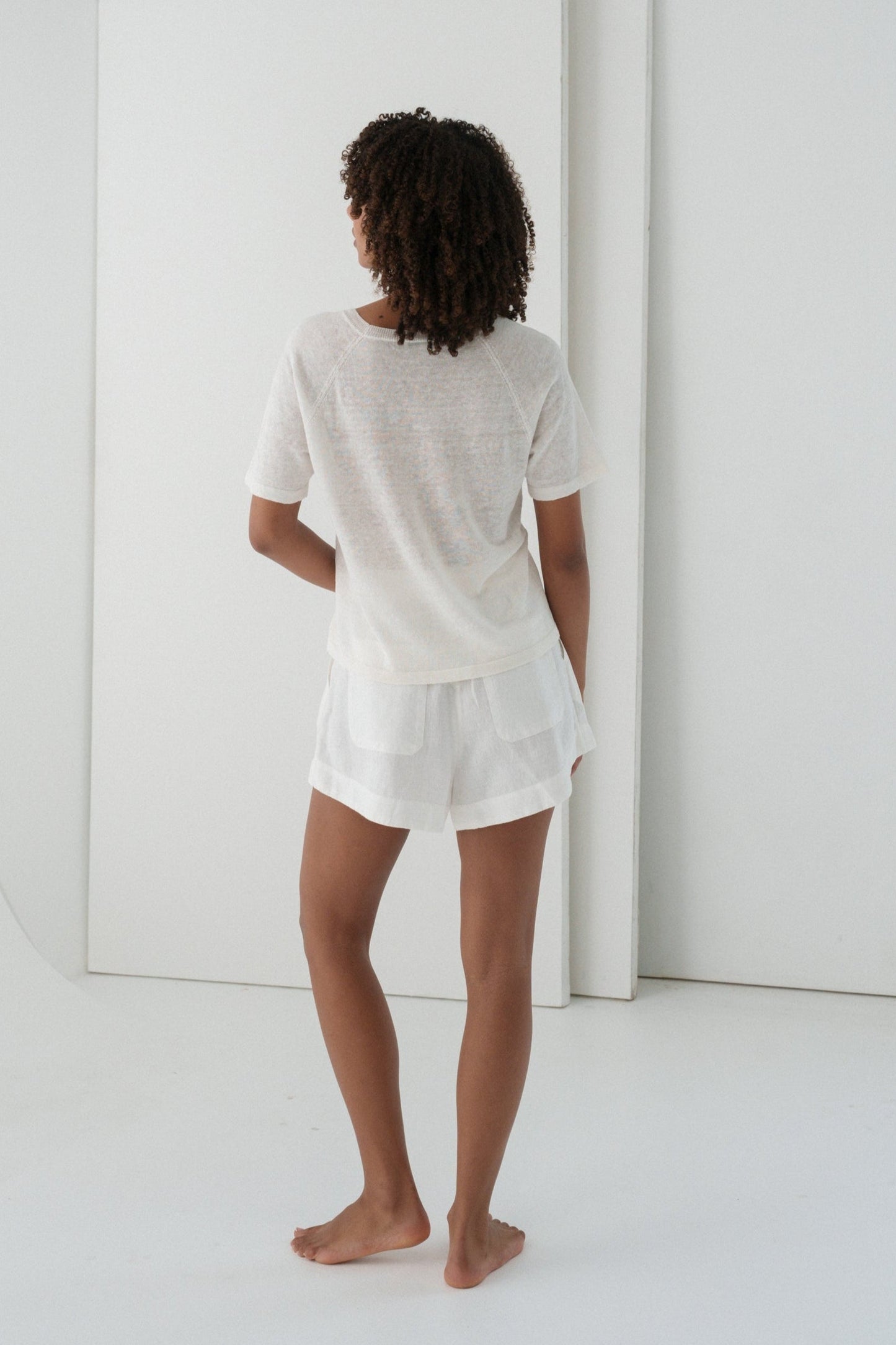Person wearing a Grace knit top in Ivory and Gaia ivory shorts set in a minimalistic setting