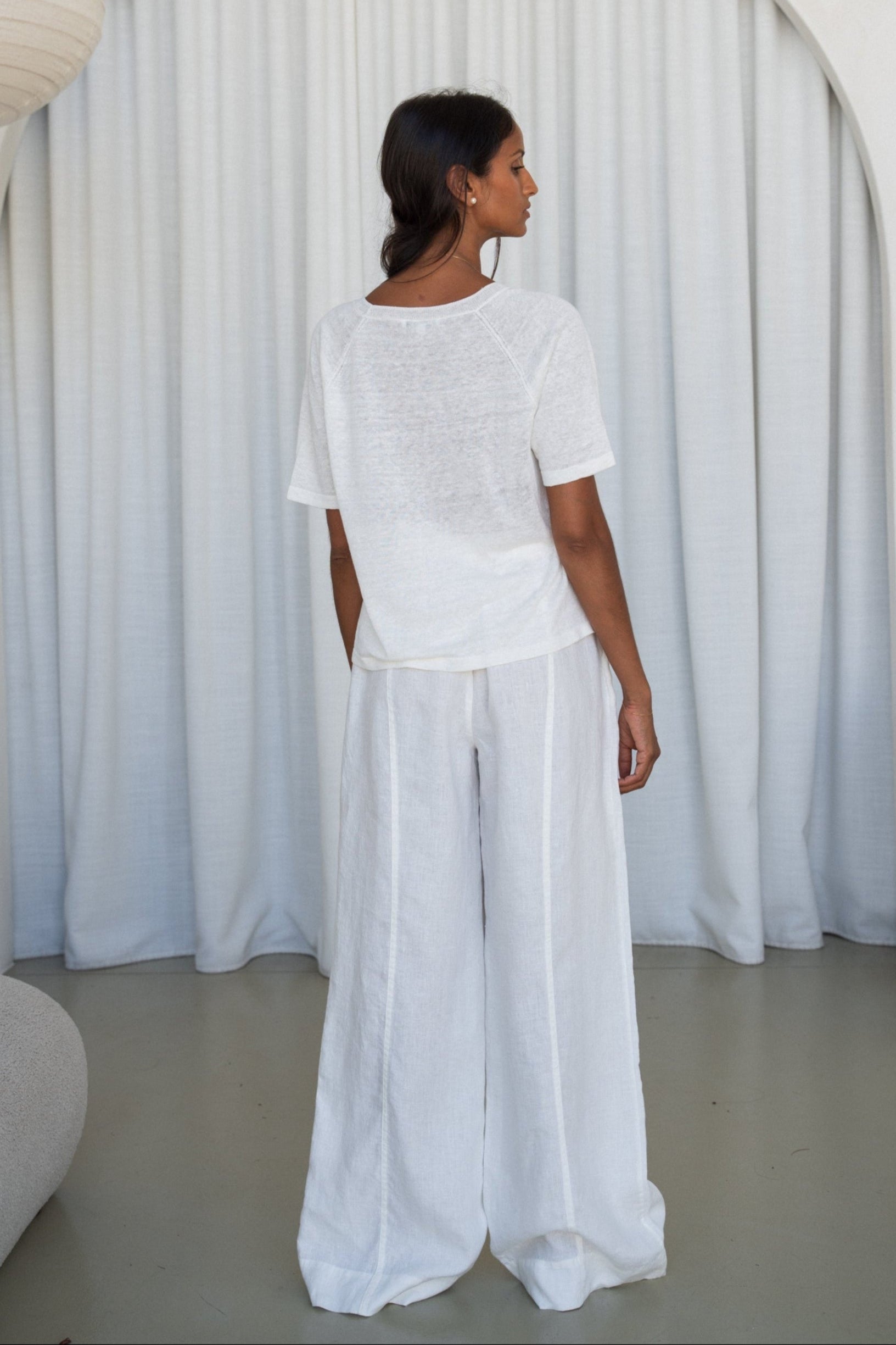 Person wearing a Grace knit top in Ivory and Oli ivory pants, back view, set against a plain white background