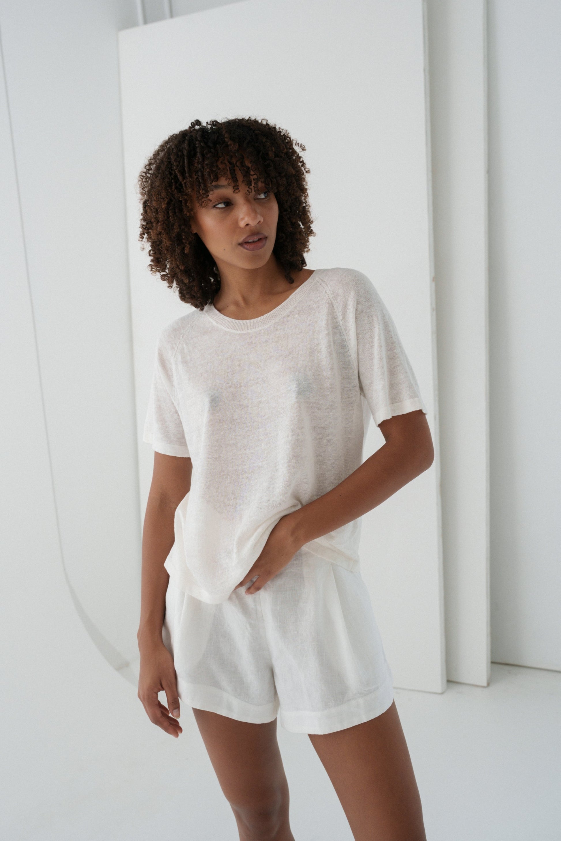 Woman wearing a Grace knit top in Ivory against a plain background