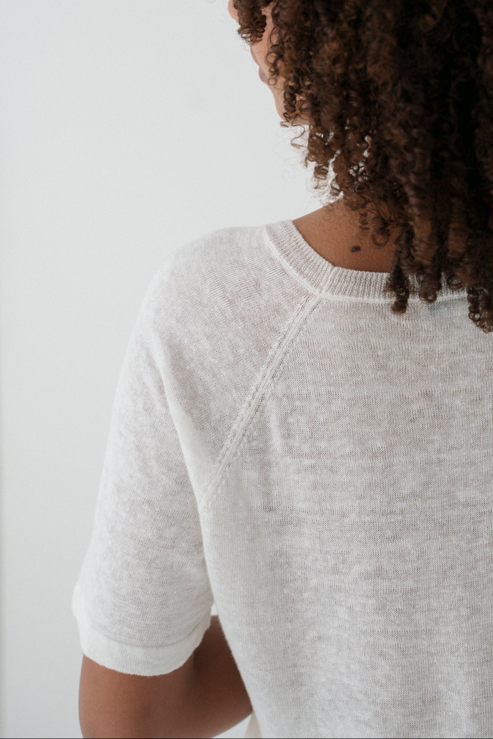 Woman wearing a Grace knit top in Ivory close up back view