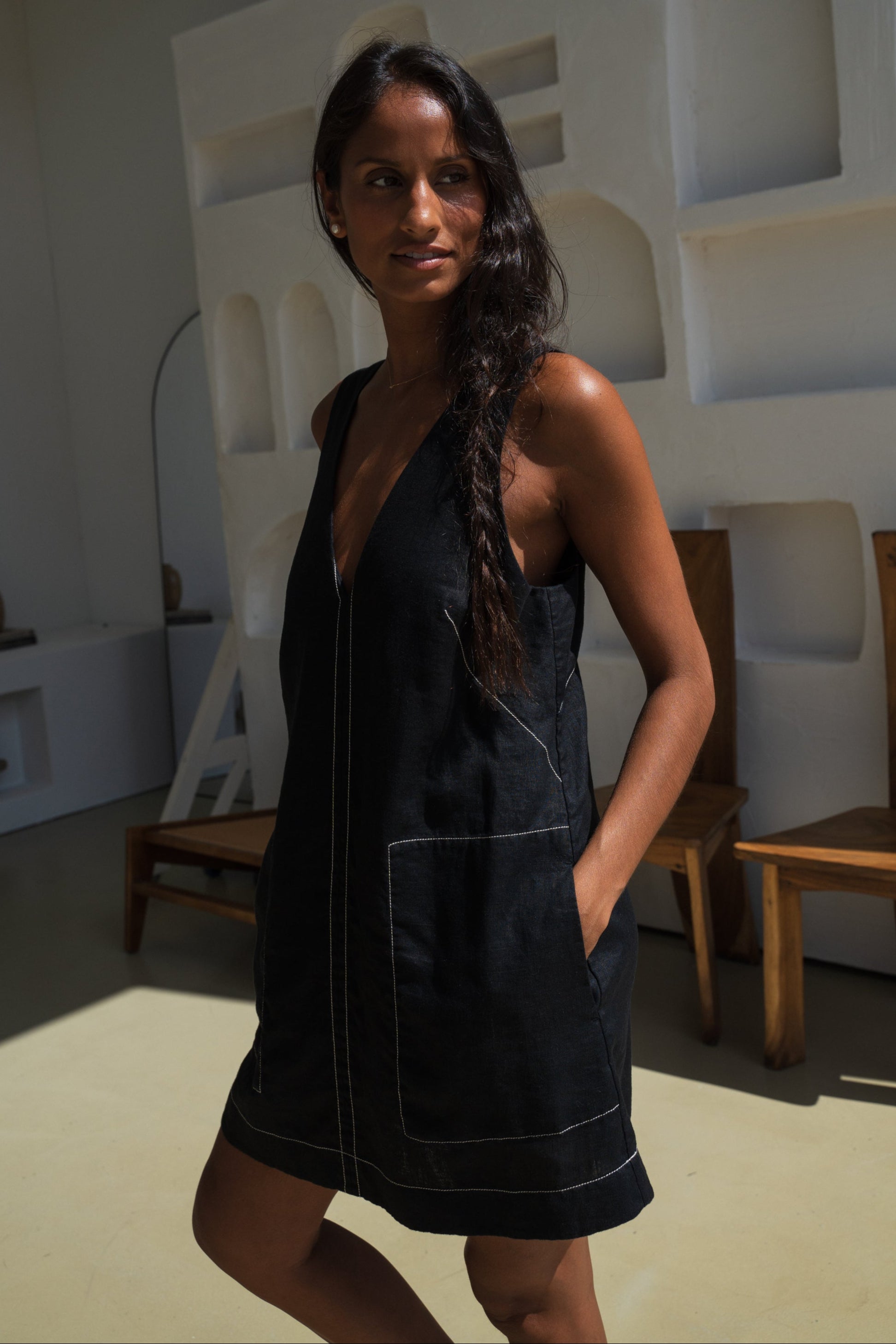 LILLY PILLY woman in an black Isla linen dress with white stitching in a modern indoor setting