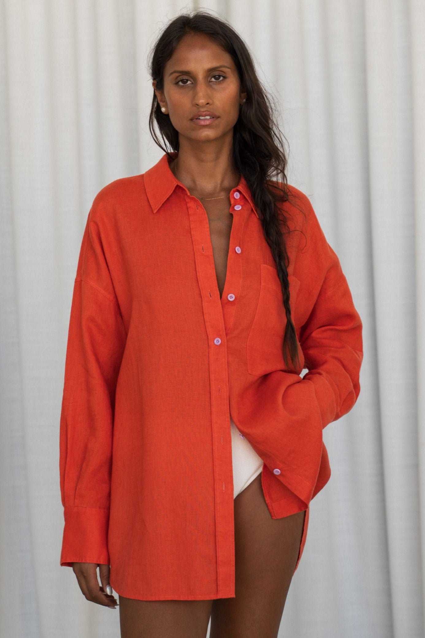 LILLY PILLY woman wearing a spritz Kirra linen shirt leaning against a   plain background