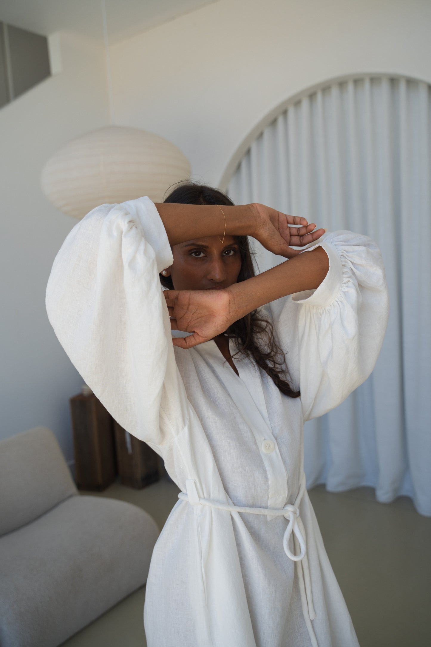 Woman in an ivory Mae linen dress in studio with arms crossed over face