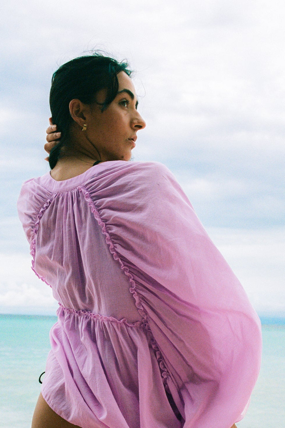 LILLY PILLY woman wearing a orchid Thalia cotton voile shirt  blouse with a blurred background by the sea